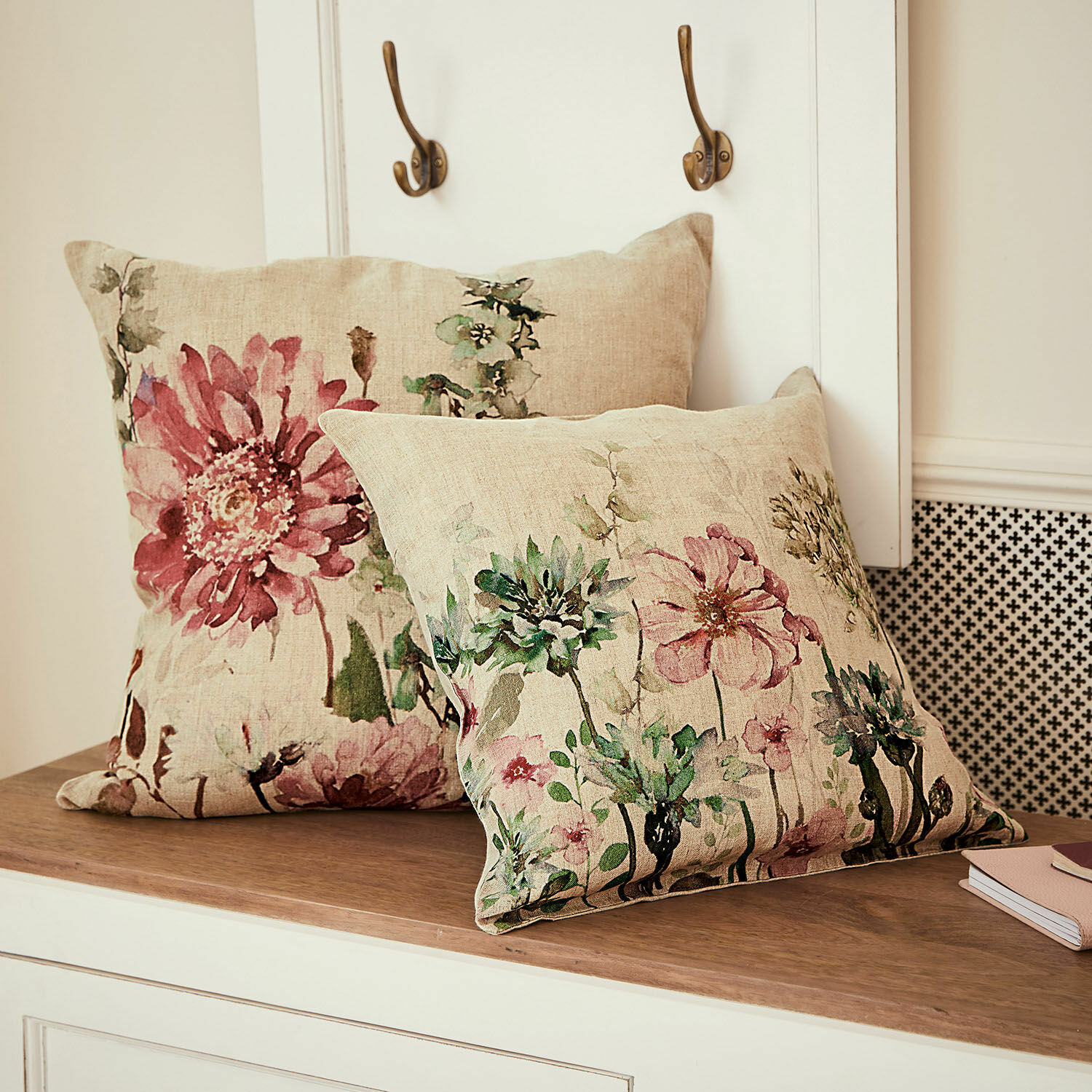 Lot de 2 housses de coussins Cornimont Coussins décoratifs en lin avec imprimé floral pastel posés sur un plateau en bois