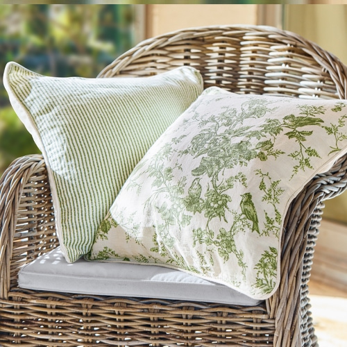 Deux coussins décoratifs verts en coton sur un fauteuil en osier, style rustique, textiles pour la maison