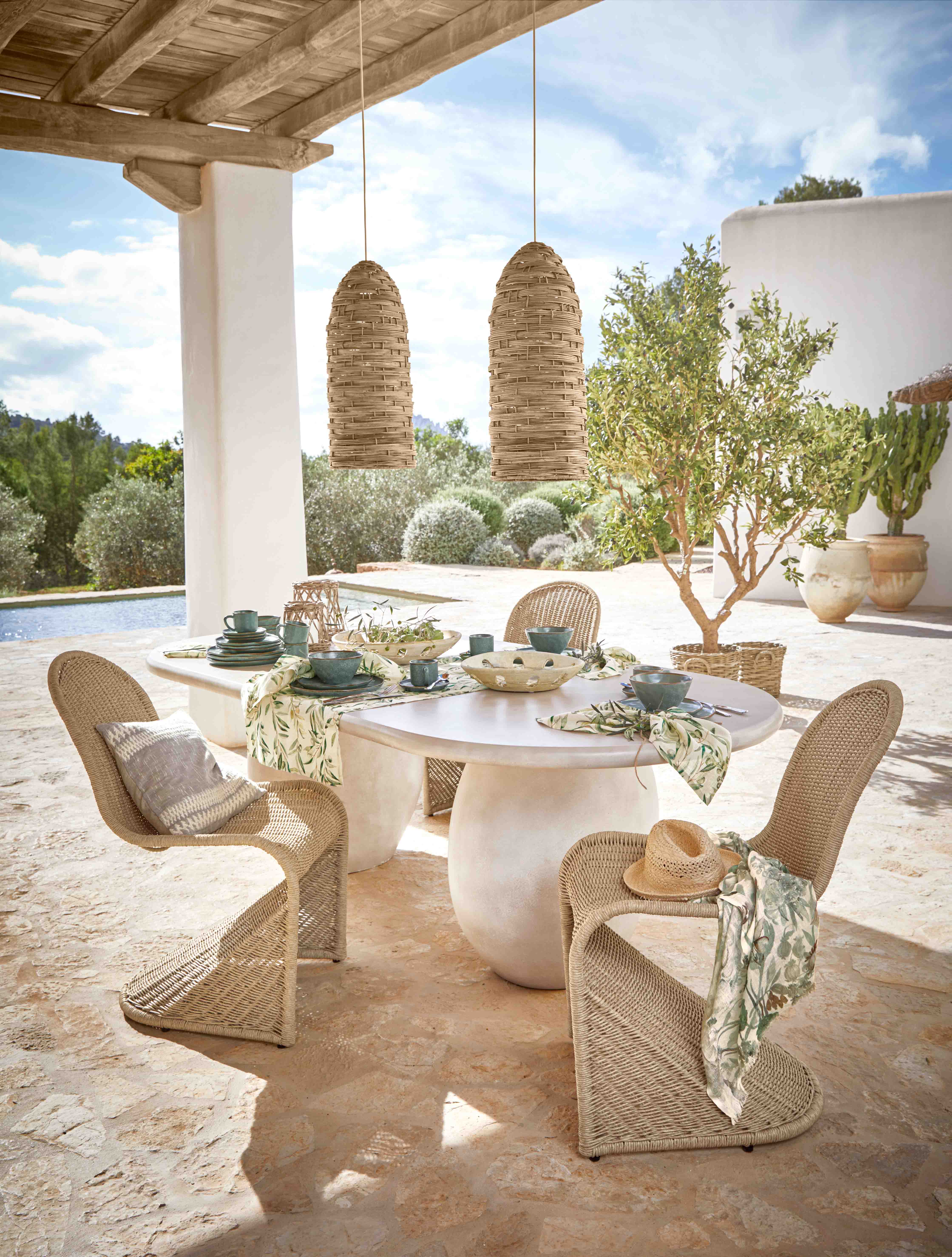 Ensemble de mobilier de jardin en osier avec chaises et table blanche sur terrasse en pierre décorée