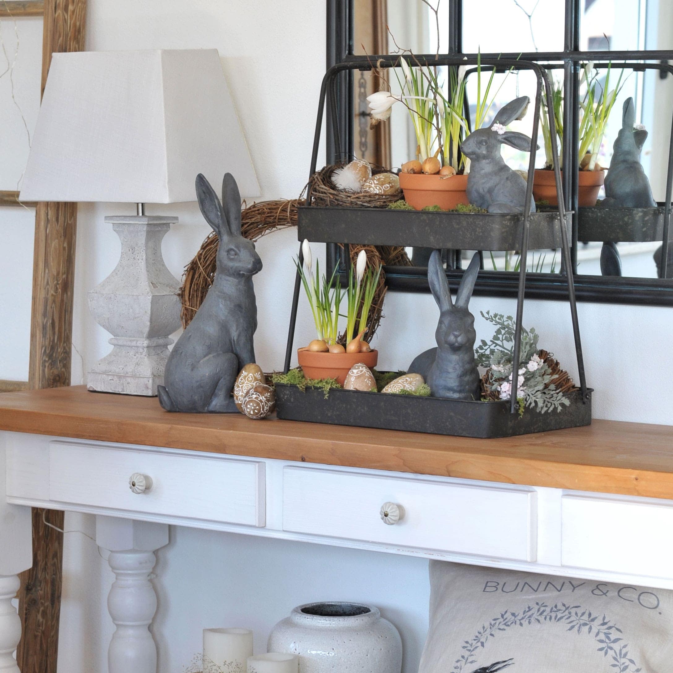 Décoration de Pâques avec lapins gris, pots de fleurs et œufs décoratifs sur une table en bois