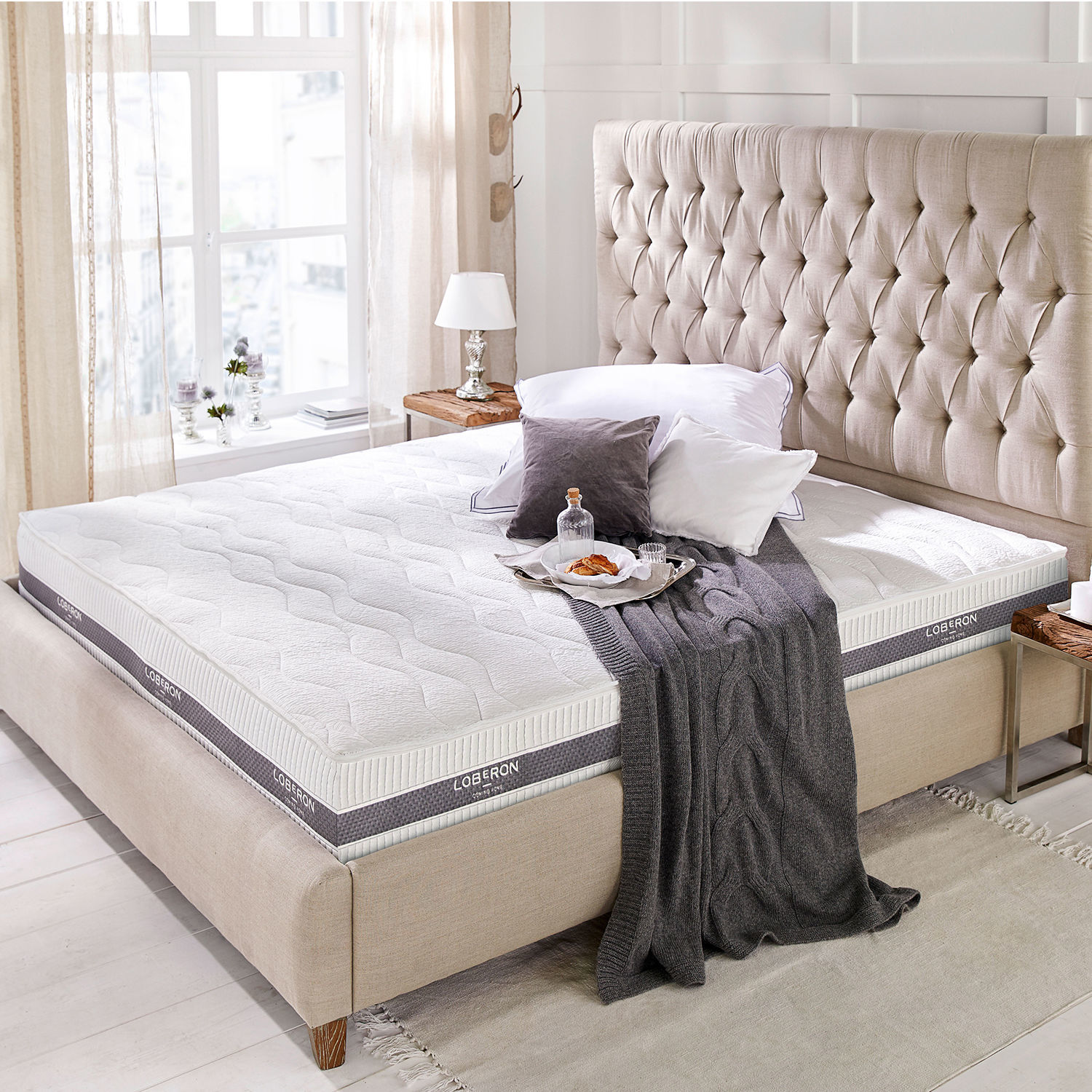 Matelas 180 x 200 Turim Matelas blanc Loberon moderne sur un lit beige avec tête de lit capitonnée dans une chambre lumineuse
