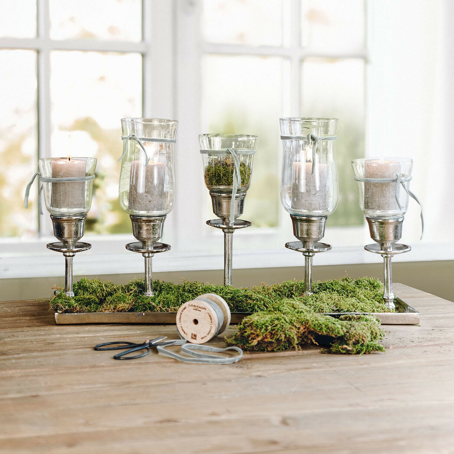 Coffret Stylebox Pâques Osterfreude Ensemble de cinq photophores en verre sur supports métalliques avec mousse verte sur une table en bois