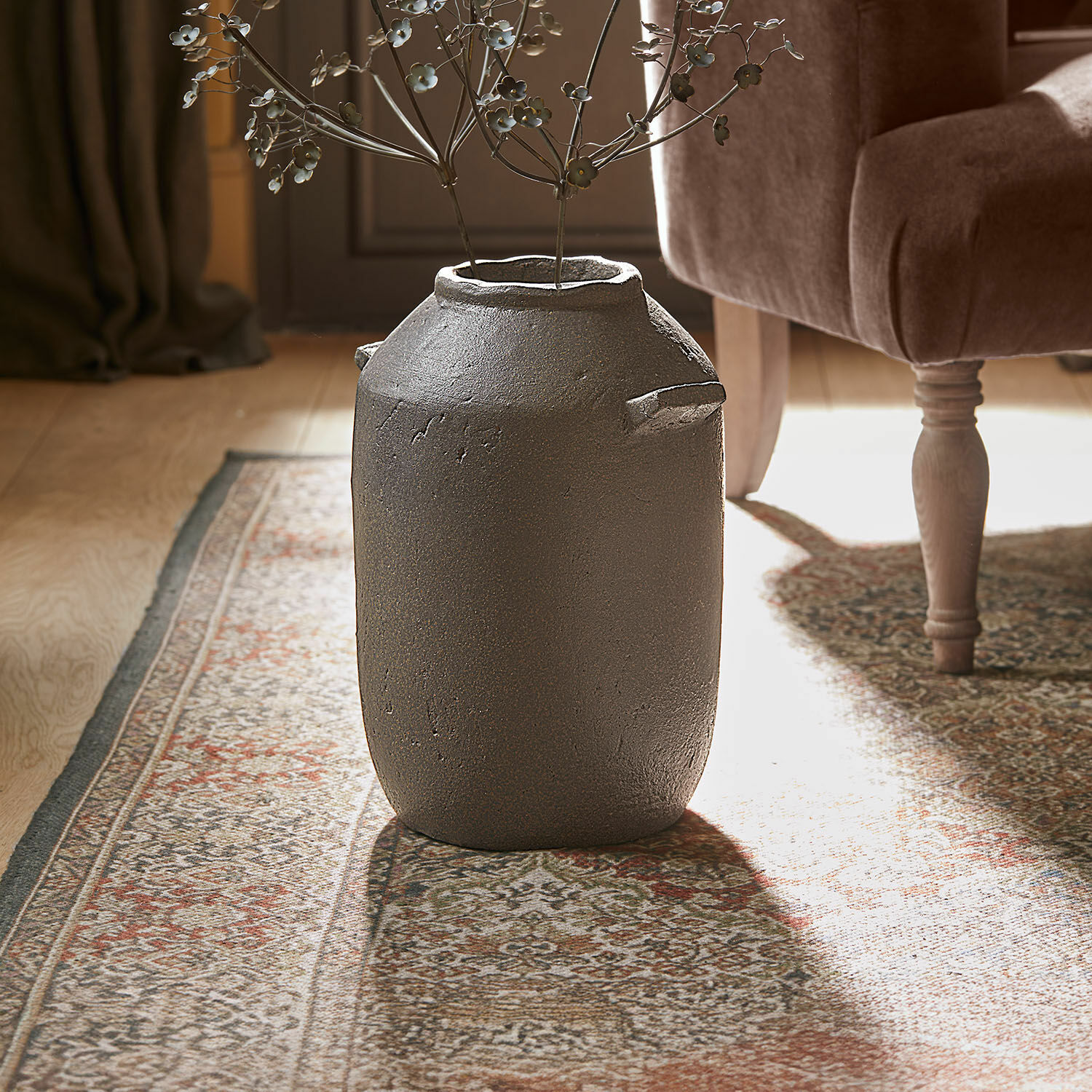 Vase Duvelle Grand vase décoratif en céramique grise posé sur un tapis dans un intérieur élégant avec fleurs métalliques