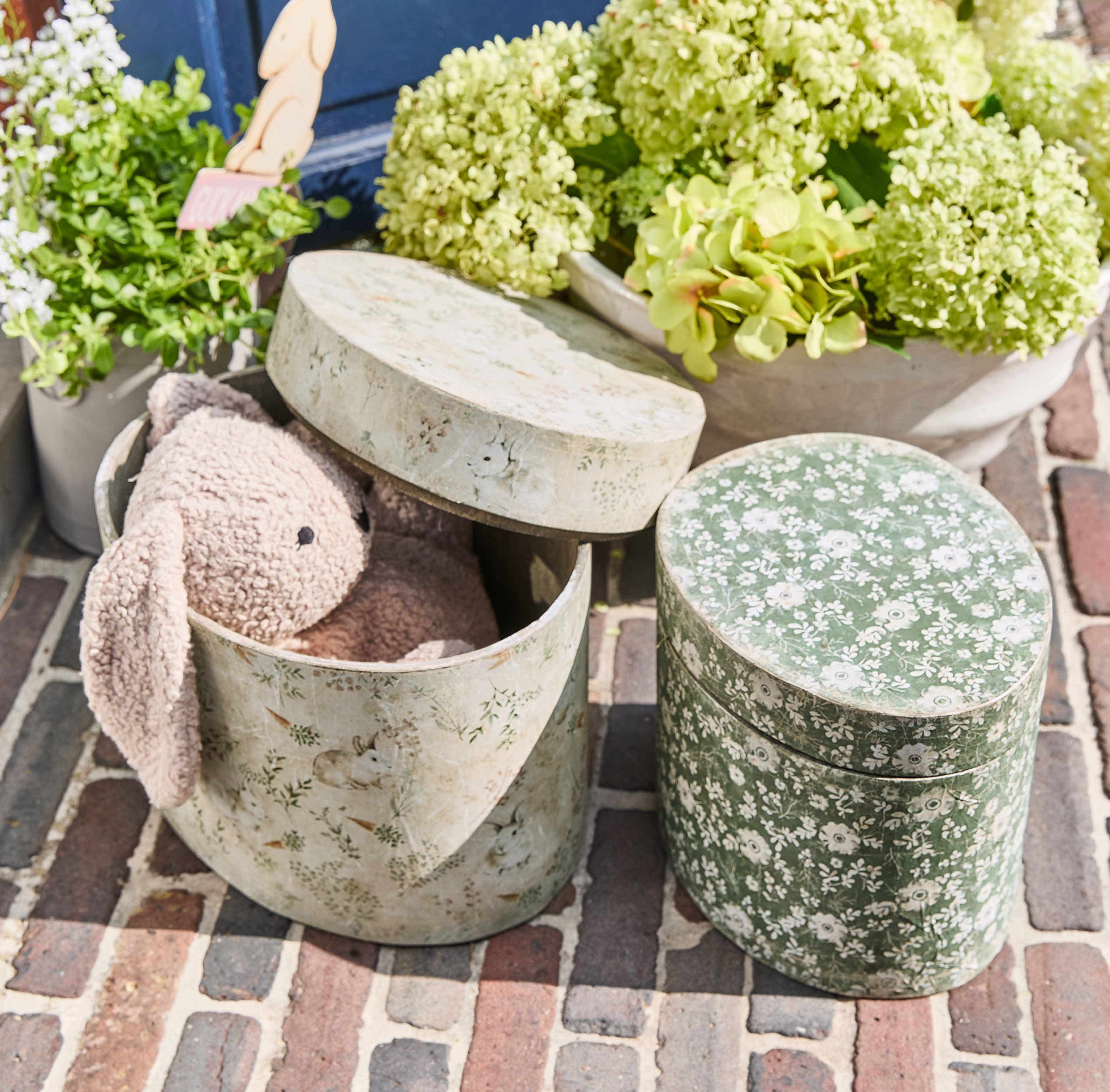 Boîtes ovales décoratives avec motifs floraux et lapins, une avec un lapin en peluche rose à l'intérieur