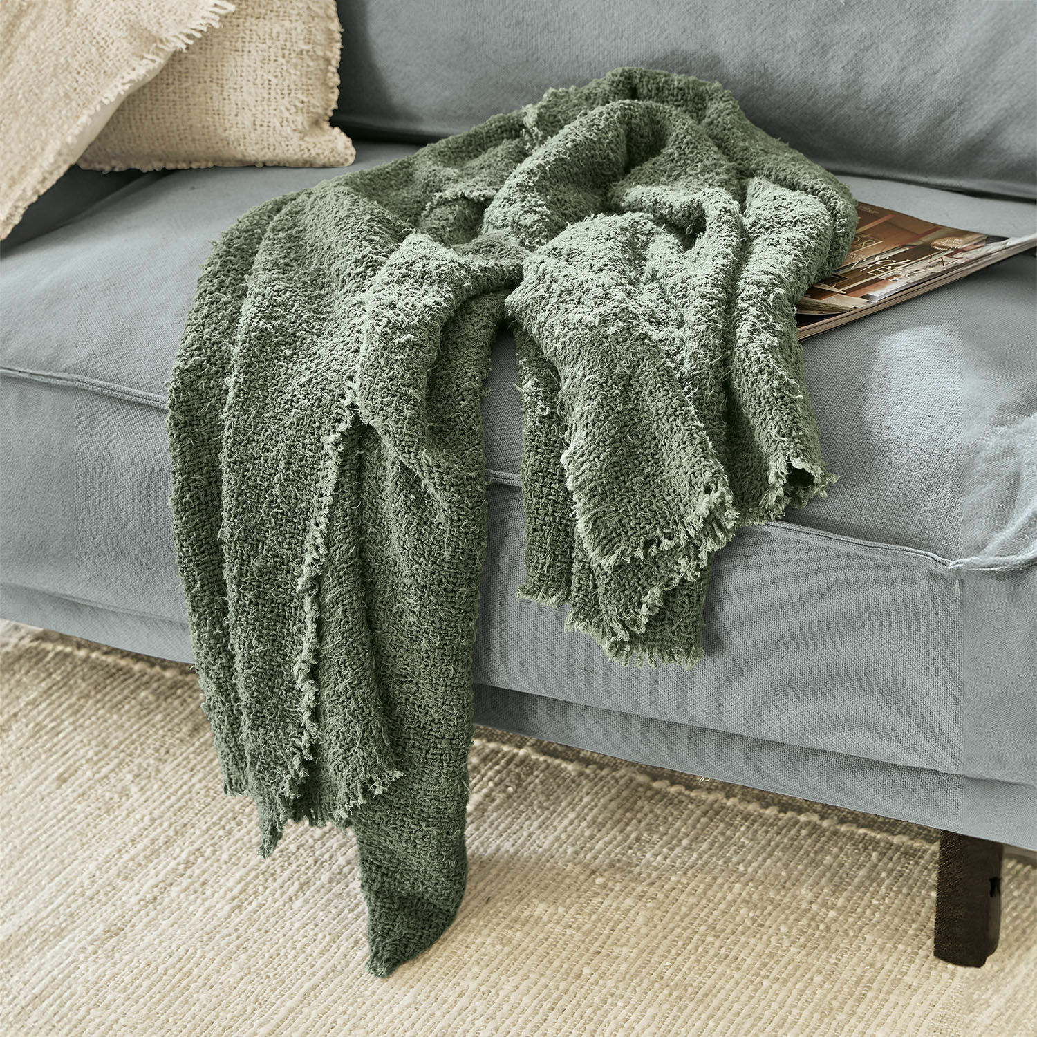 Plaid Juliana Plaid vert en coton doux sur un canapé gris, accessoire décoratif et confortable pour le salon