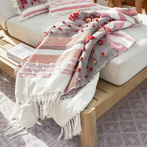 Plaid décoratif en coton blanc, rose et gris avec franges et pompons, parfait pour le salon cosy