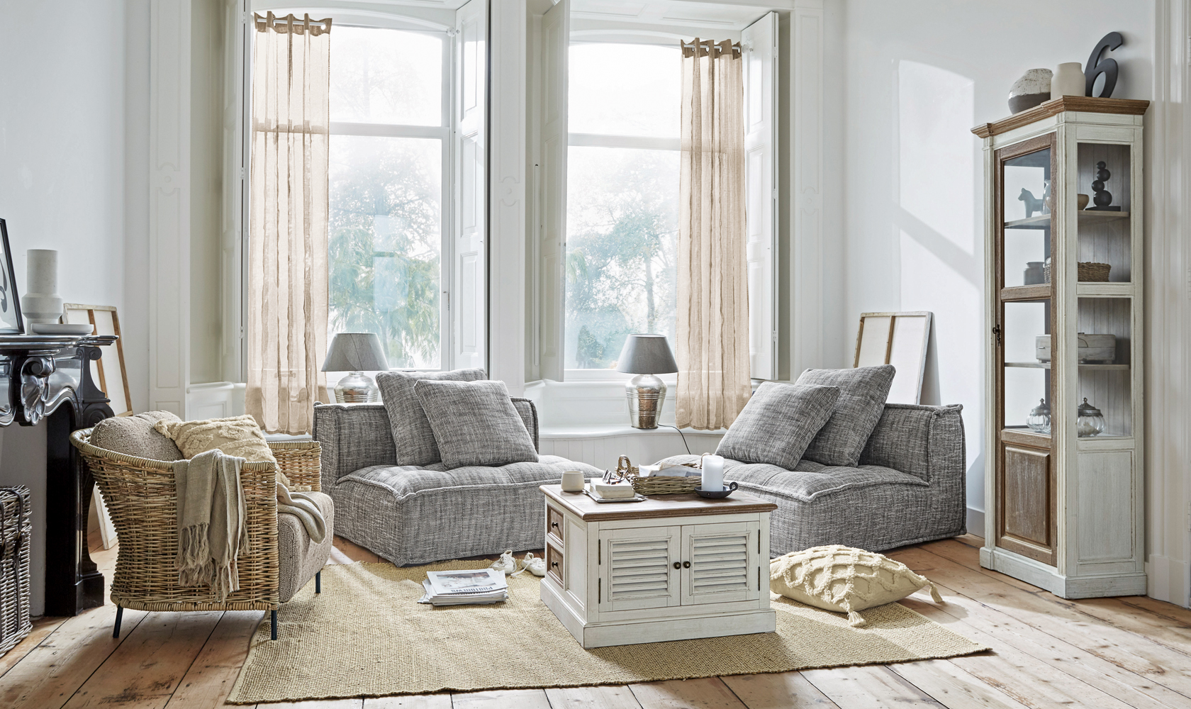 Salon lumineux avec fauteuils gris et meuble en bois blanc sur tapis en jute, style scandinave moderne