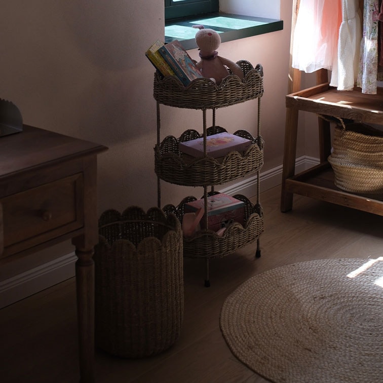 Étagère à trois niveaux en osier naturel avec livres et jouets dans une pièce chaleureuse