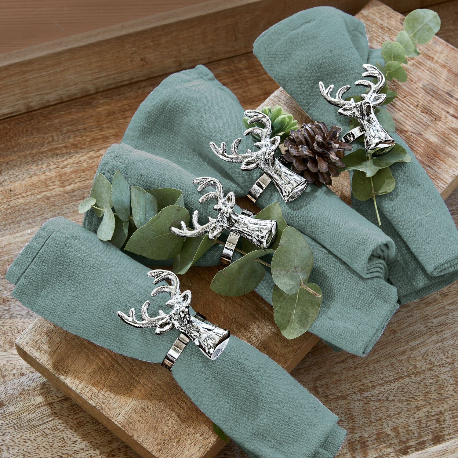 Lot de 6 ronds de serviettes Bisoro Ensemble de quatre serviettes en lin vert avec anneaux en métal tête de cerf sur plateau en bois