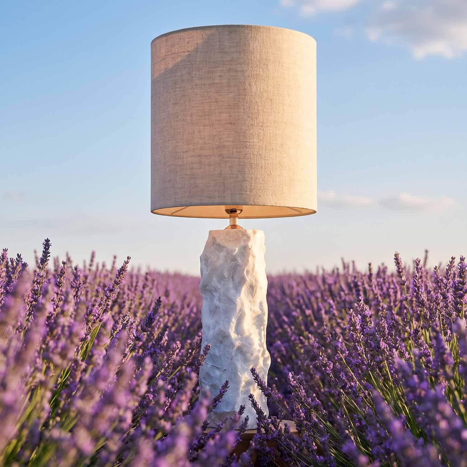 Lampe de table avec base en marbre blanc et abat-jour beige posée dans un champ de lavande, déco intérieure