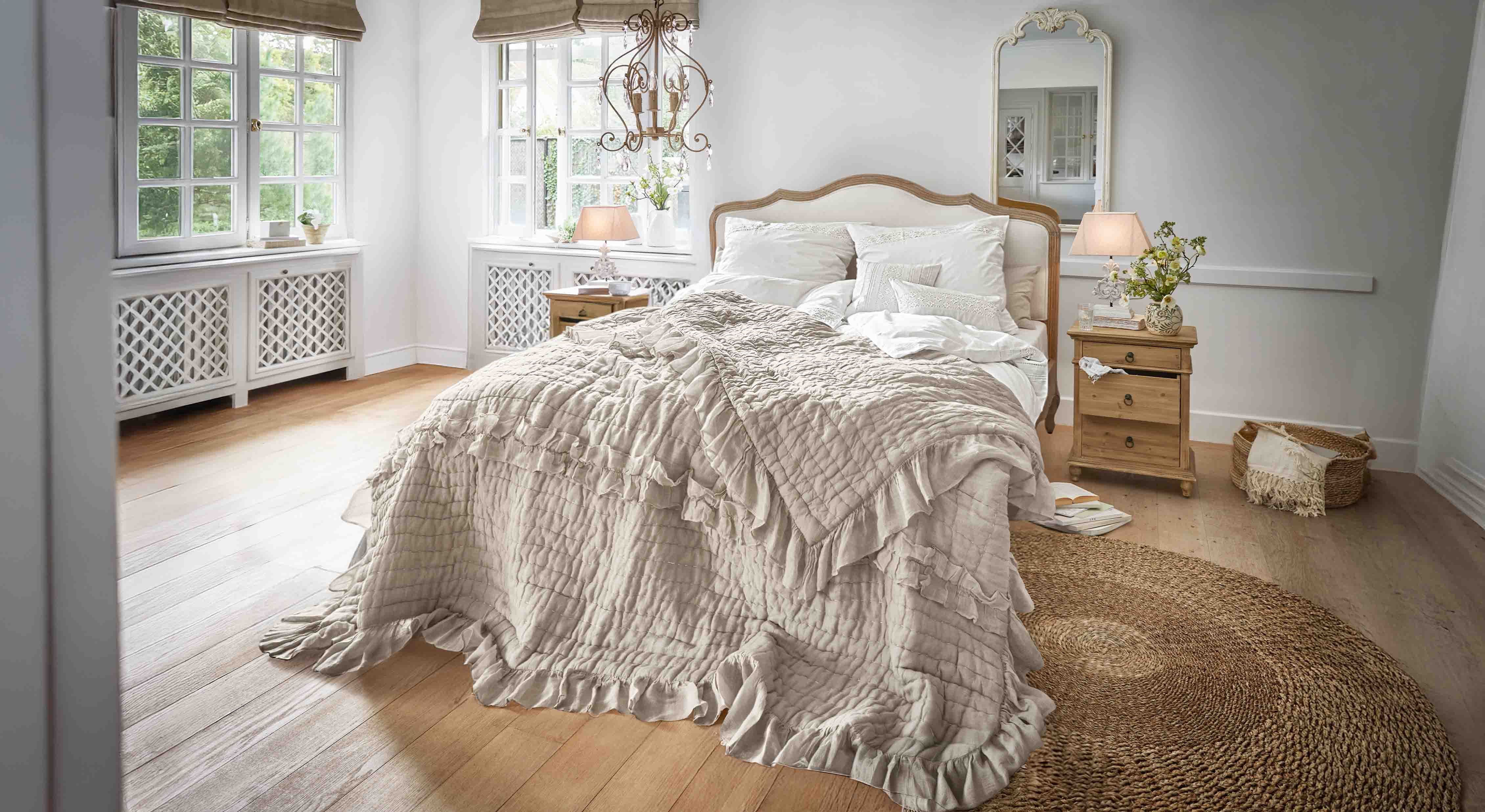 Chambre chaleureuse avec lit en couvre-lit beige à volants et meubles en bois naturel