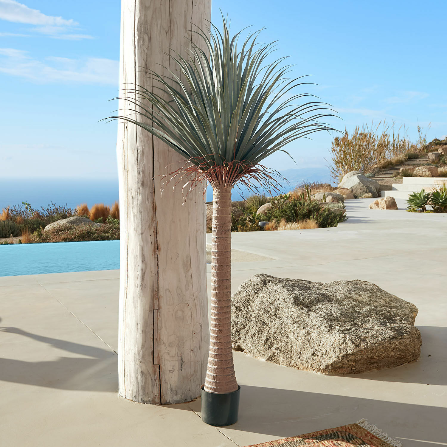 Palmier décoratif Remivon Palmier artificiel en pot avec tronc marron et feuilles vertes sur terrasse avec vue sur mer