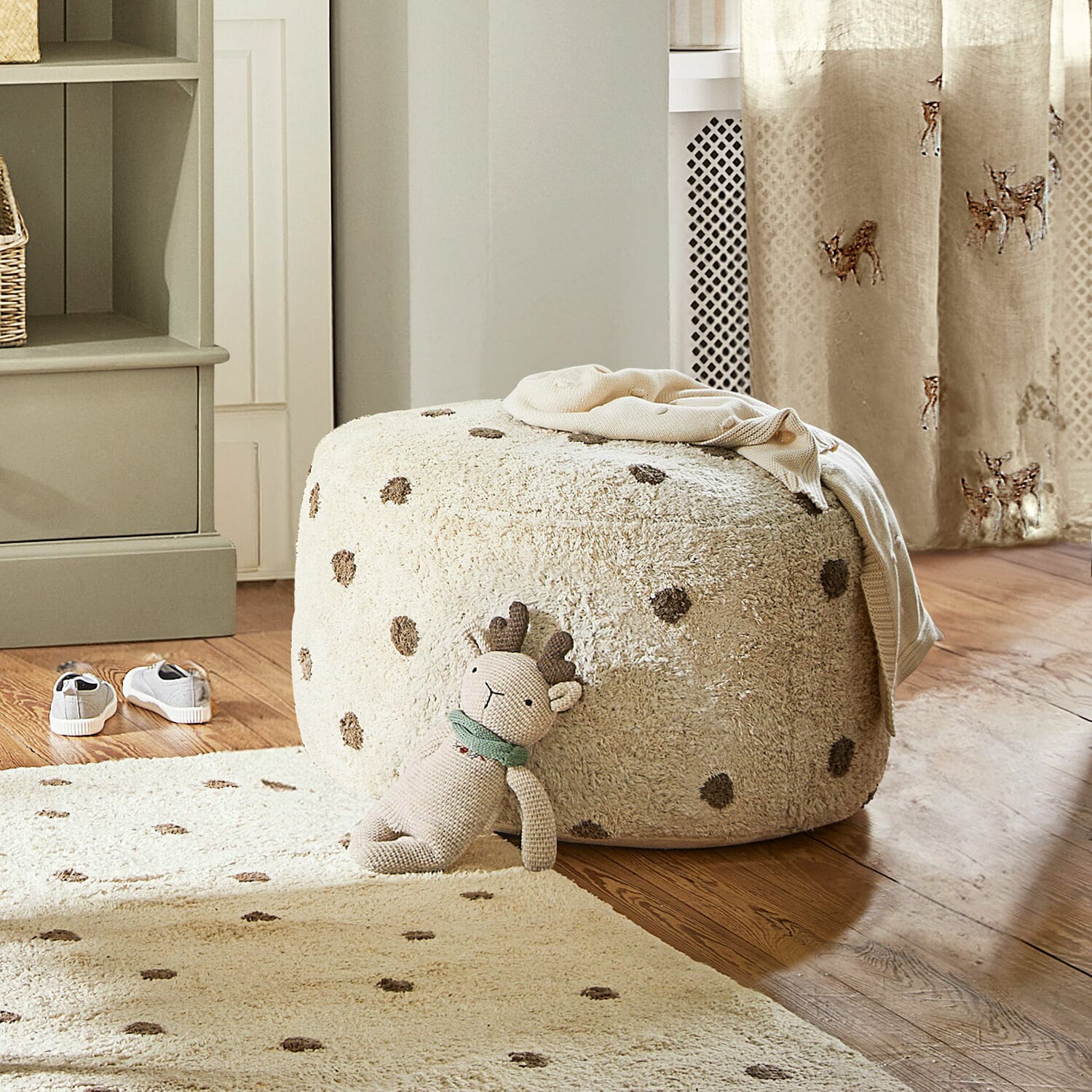 Pouf Thivalie Pouf beige en tissu doux à pois sur parquet avec peluche et tapis assorti dans la pièce