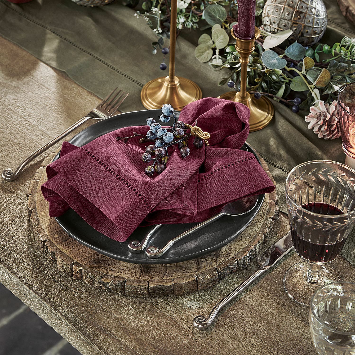 Lot de 4 serviettes Covent Garden Sous-assiette en bois rustique avec assiette noire et serviette en lin bordeaux sur table en bois