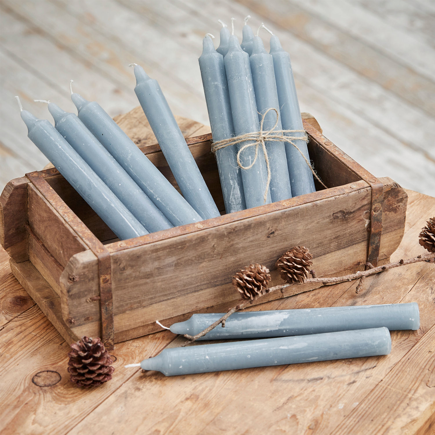 Lot de 12 bougies Bauceau Lot de bougies bleues en cire dans une boîte en bois sur une table rustique avec des pommes de pin