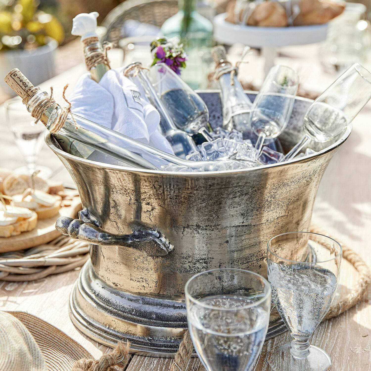 Seau à champagne Cerisé Seau à glace en métal avec bouteilles et flûtes à champagne sur une table ensoleillée