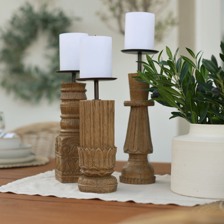 Trois bougeoirs en bois avec bougies blanches sur une table, décoration intérieure naturelle