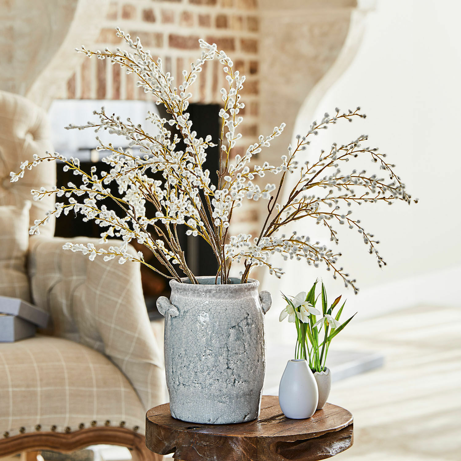 Lot de 3 branches décoratives Palmyra Vase en céramique grise avec branches de chatons sur une table en bois dans un salon lumineux