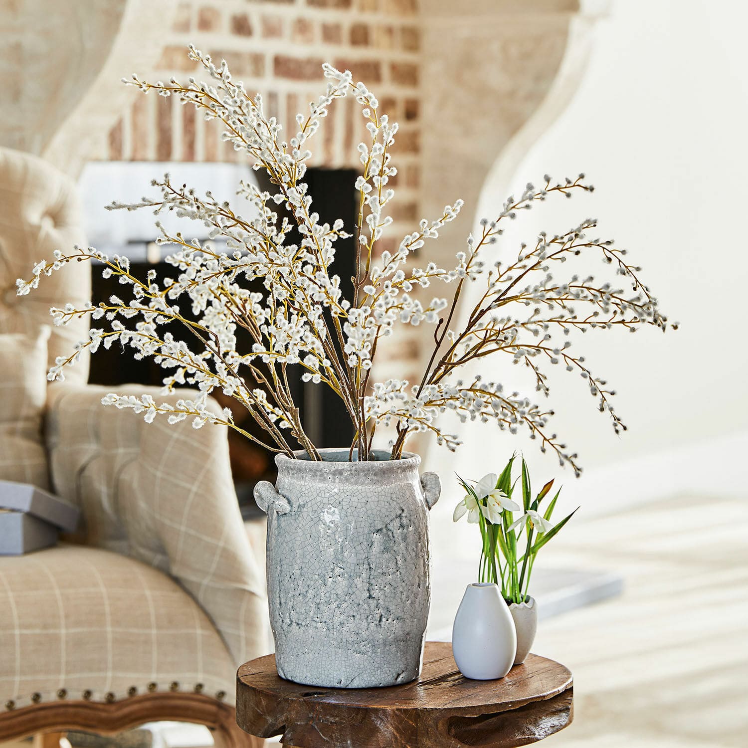 Lot de 3 branches décoratives Palmyra Vase en céramique grise avec branches de chatons sur une table en bois dans un salon lumineux