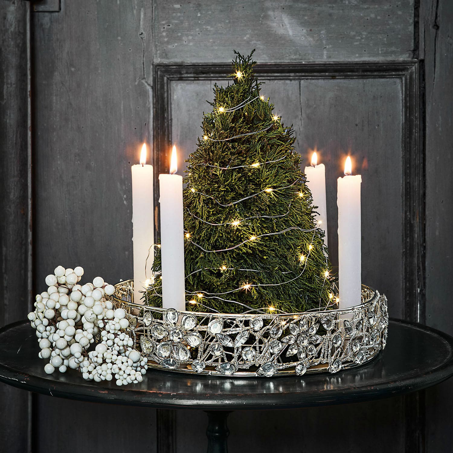 Arbre décoratif Moran Bougeoir décoratif avec bougies blanches et sapin vert orné de guirlandes lumineuses LED sur table noire