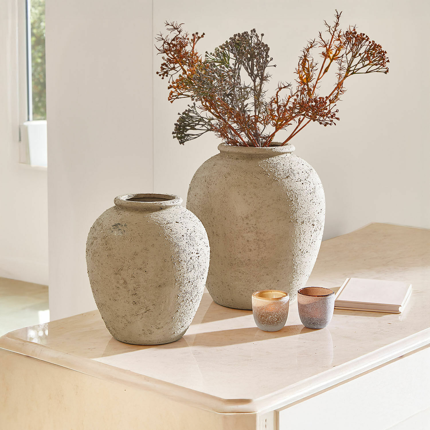 Lot de 2 vases Zaviro Deux grands vases en béton gris sur un meuble clair avec branches sèches et bougies décoratives