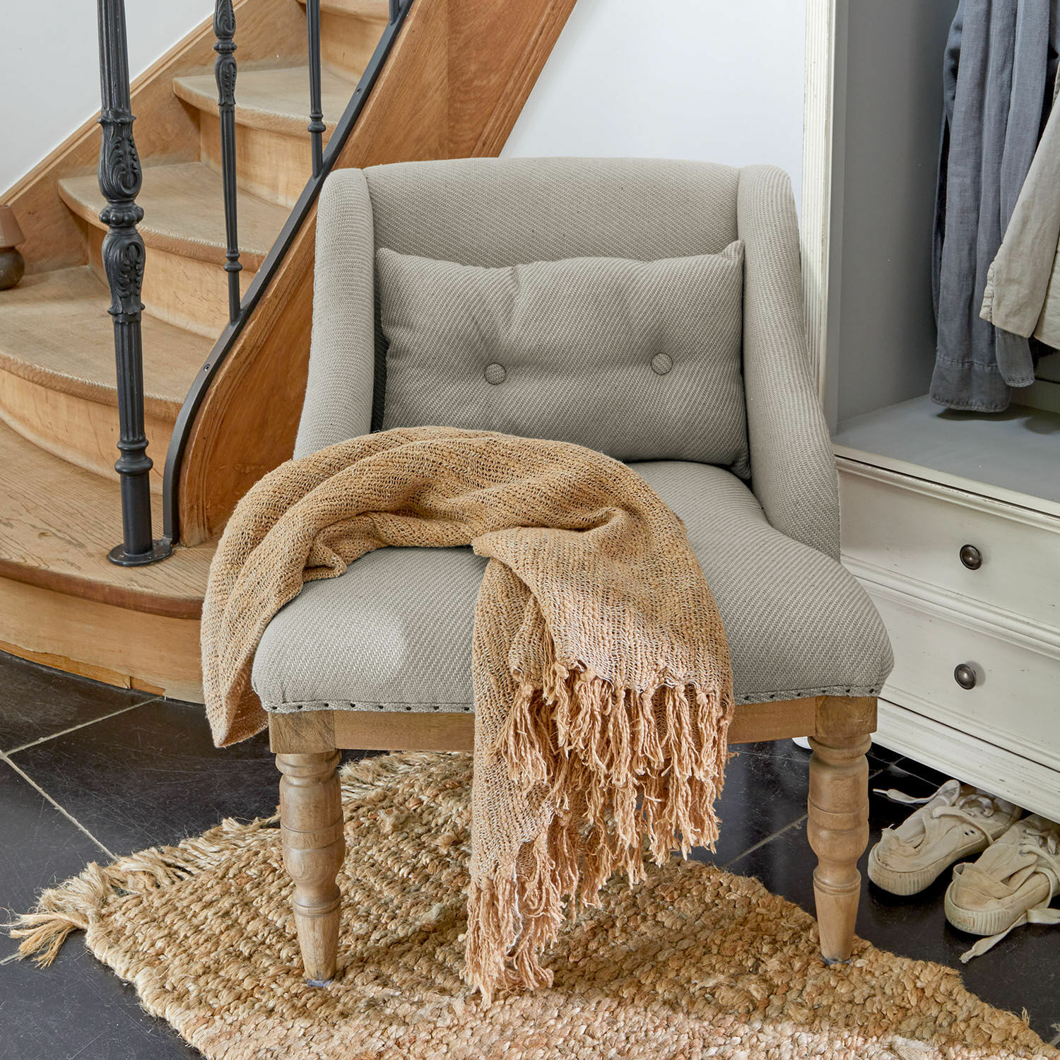Fauteuil Lac d'Or Fauteuil gris en tissu avec pieds en bois et plaid beige tissé sur un tapis en jute