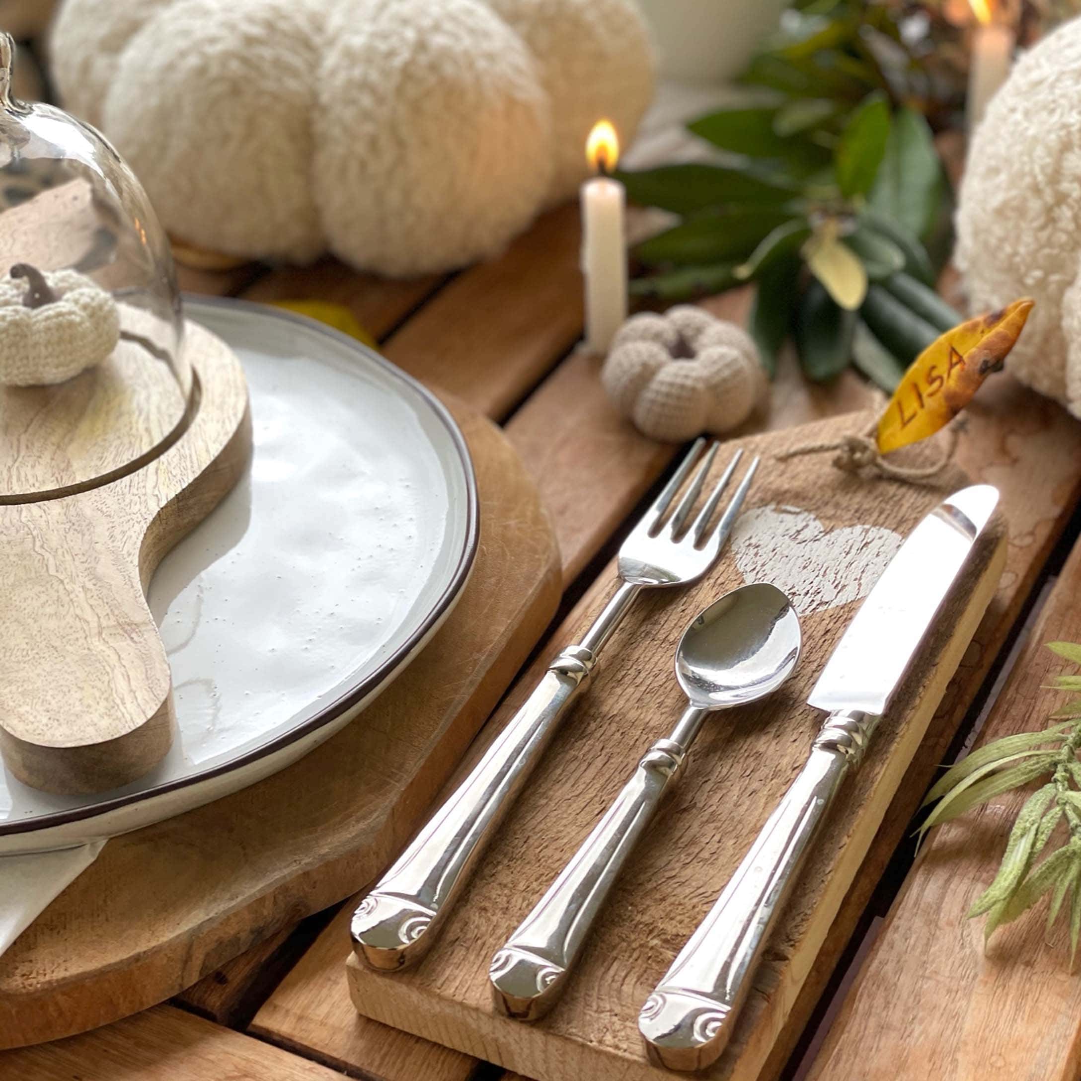 Table rustique en bois avec décoration d'automne, couverts en métal et citrouilles tricotées blanches