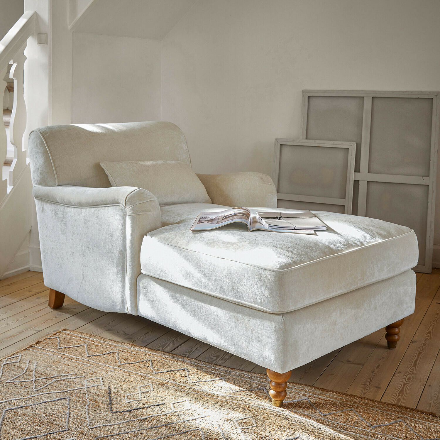Fauteuil beige en tissu doux avec repose-pieds et pieds en bois dans un salon lumineux