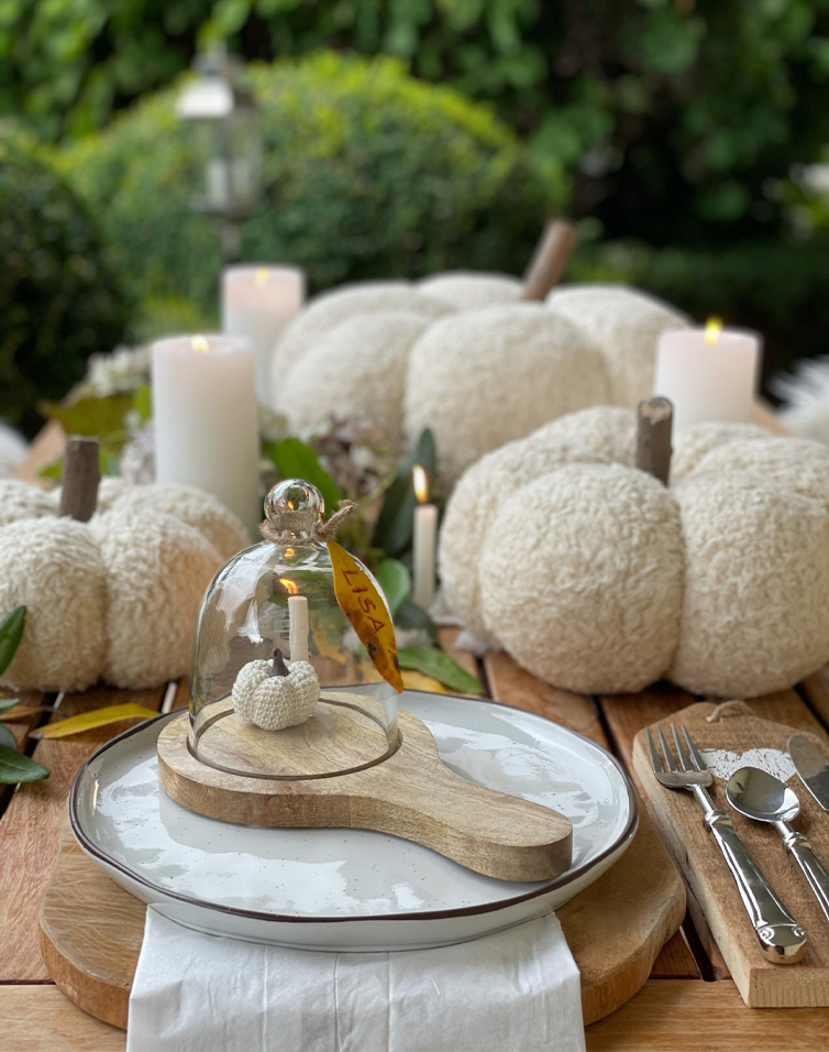 Table d'automne décorée de citrouilles blanches en tissu et bougies sur une table en bois