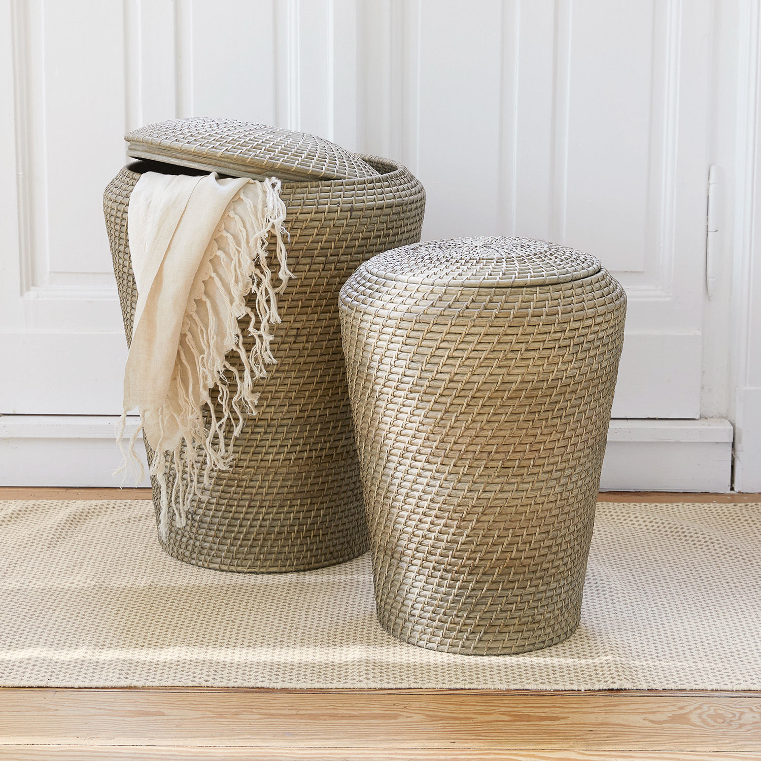 Lot de 2 paniers à linge Nora Deux paniers en rotin beige avec couvercles sur un tapis, rangements pratiques pour la maison