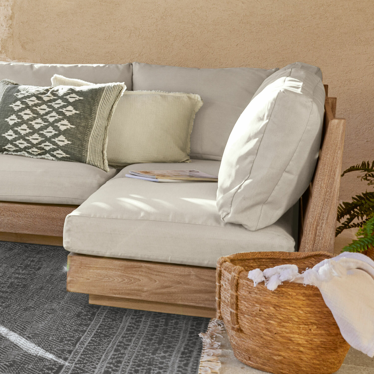 Canapé d'angle en tissu gris clair avec cadre en bois, coussin décoratif et panier en osier avec tissu