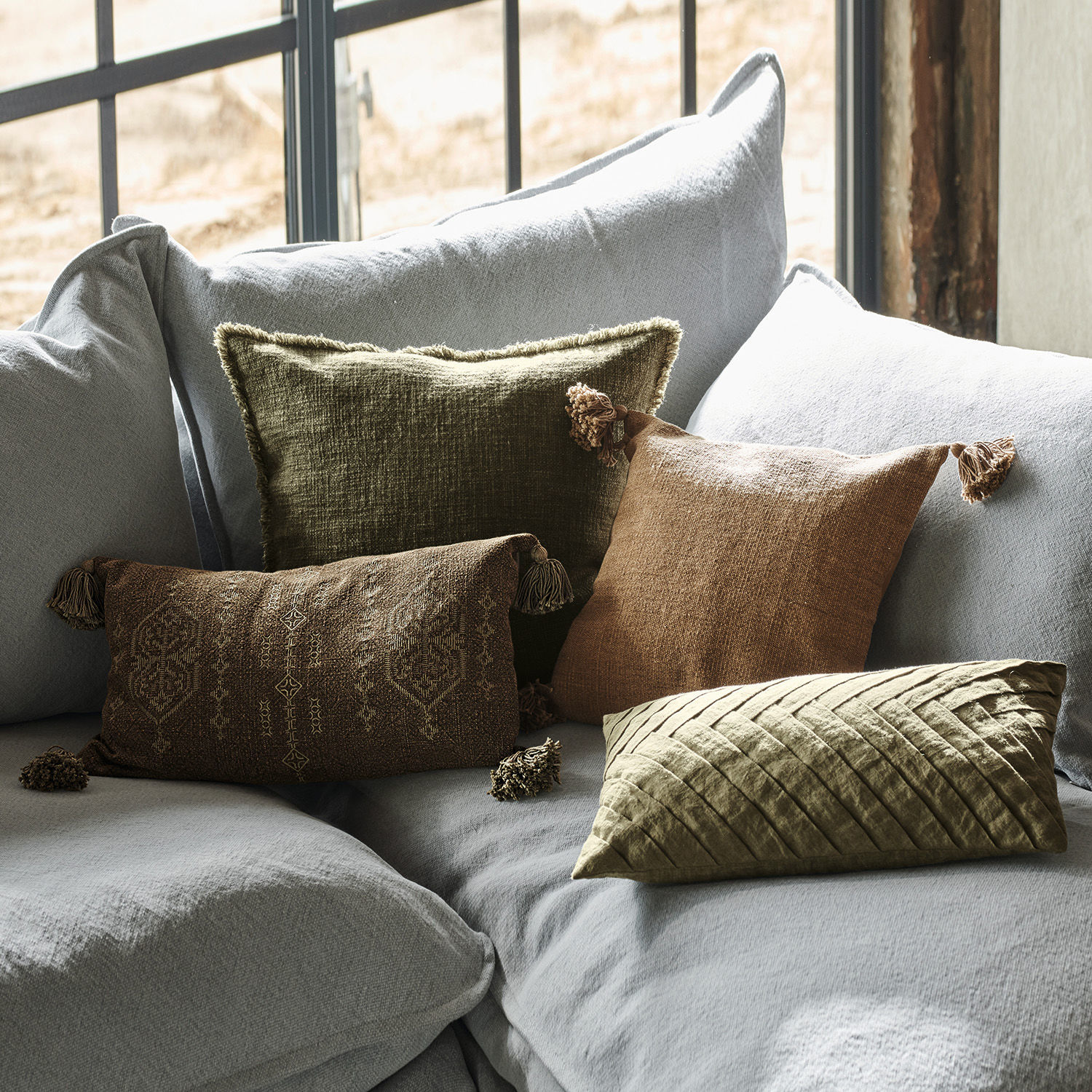 Lot de 4 housses de coussins Donagh Ensemble de coussins décoratifs en tissu marron et vert sur un canapé gris clair