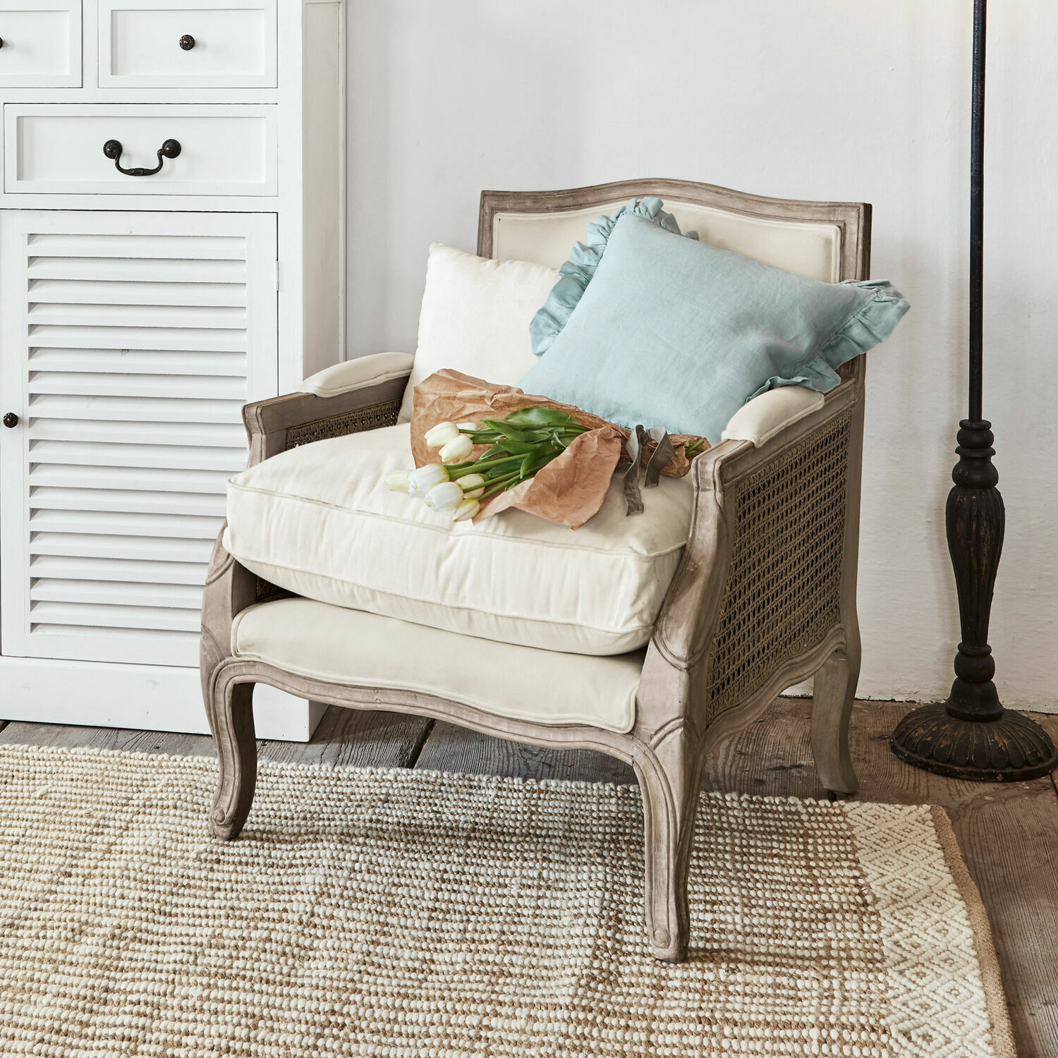 Fauteuil Alfort Fauteuil classique en bois et tissu crème avec coussins et bouquet de tulipes blanches
