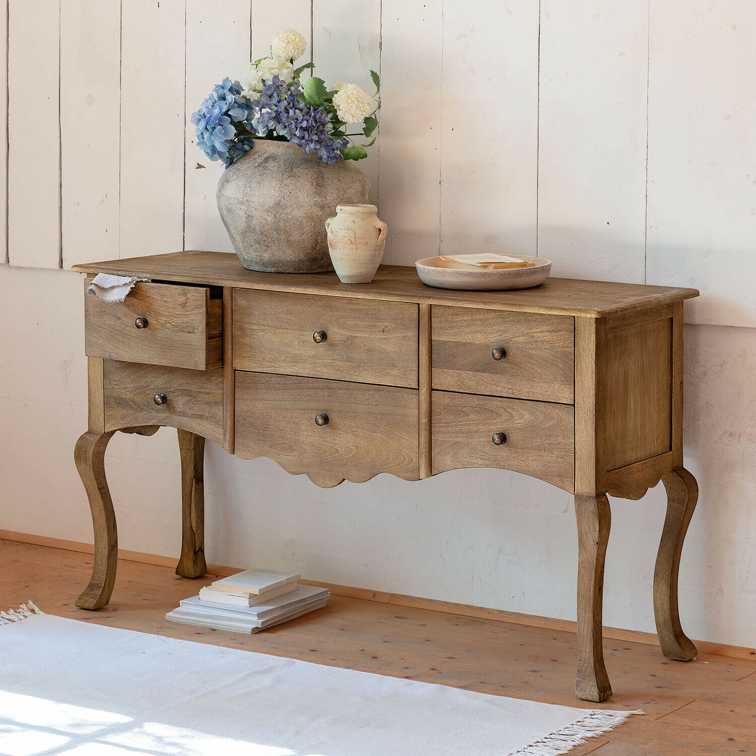 Commode Norelia Console en bois naturel avec quatre tiroirs et pieds sculptés dans un style classique