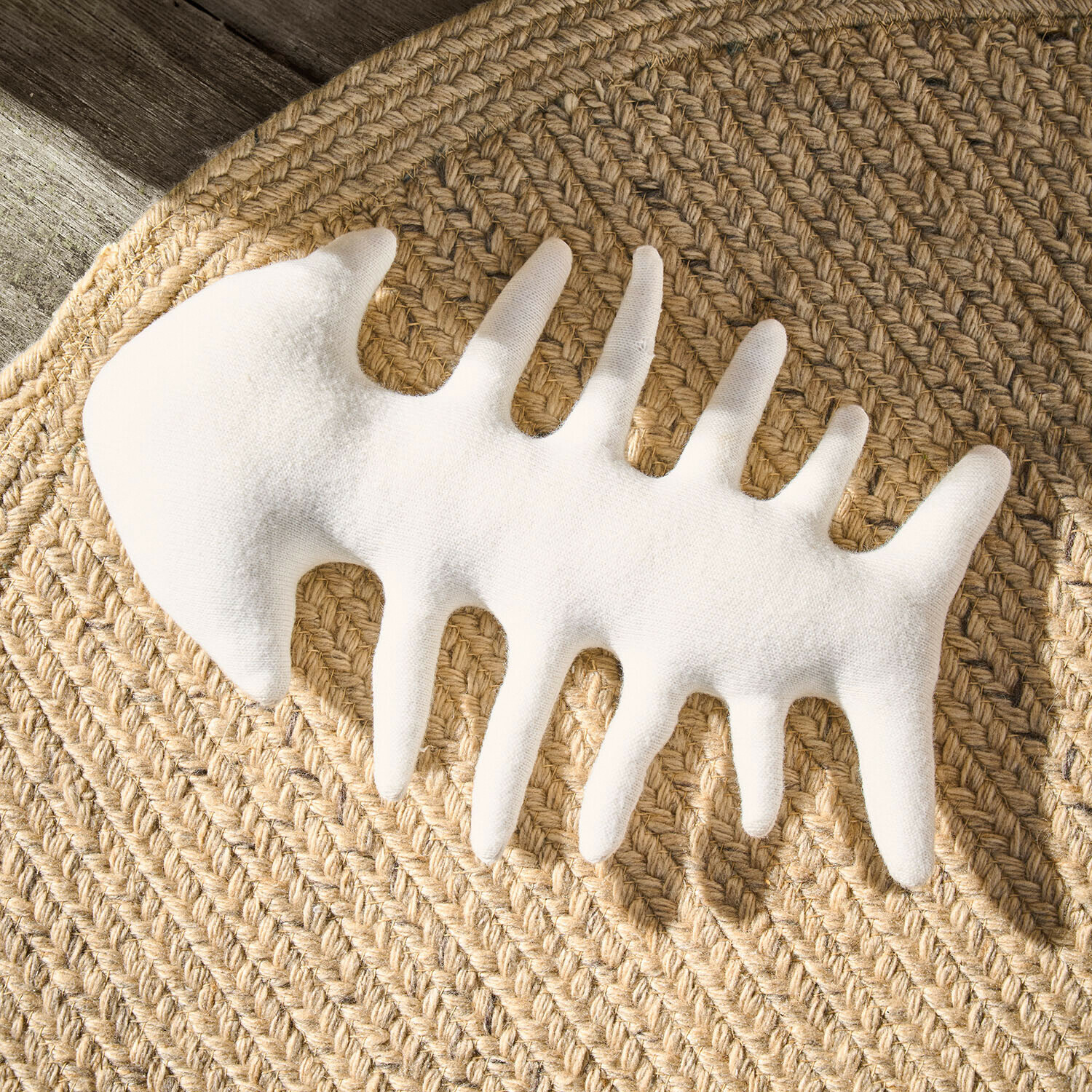 Décoration blanche en forme d'ossature de poisson en tissu sur tapis en jute tressée