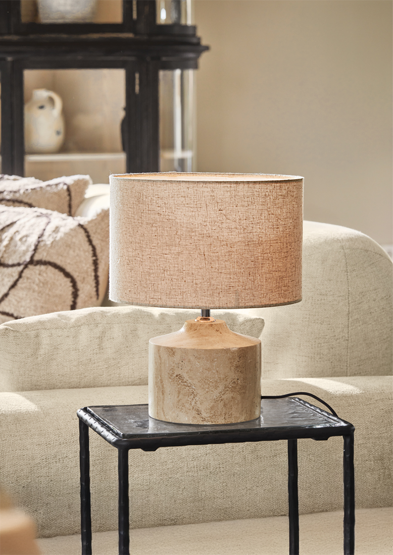 Lampe de table avec abat-jour beige et base en céramique couleur sable sur une table noire