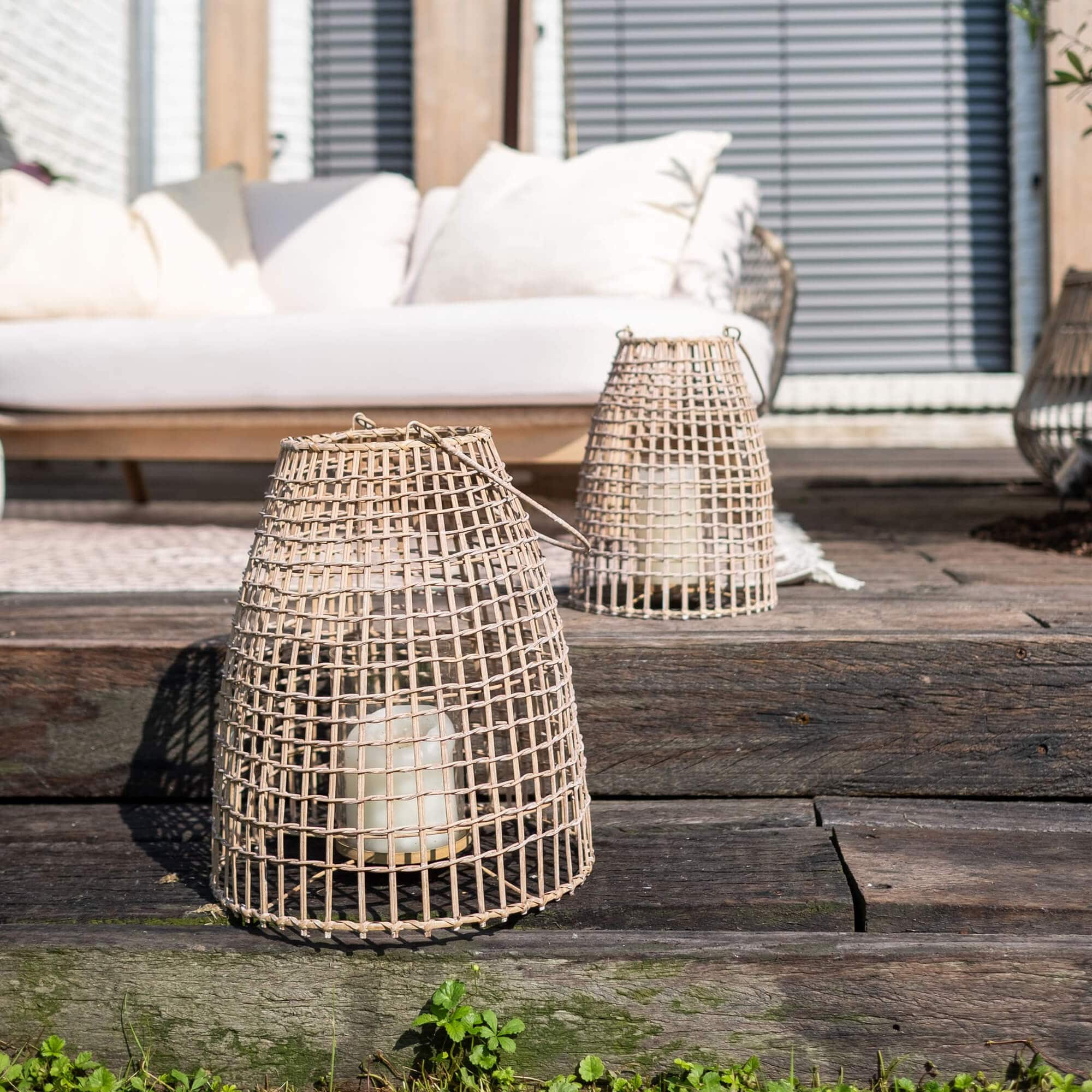 Lanterne en osier naturel avec bougie blanche sur terrasse en bois rustique