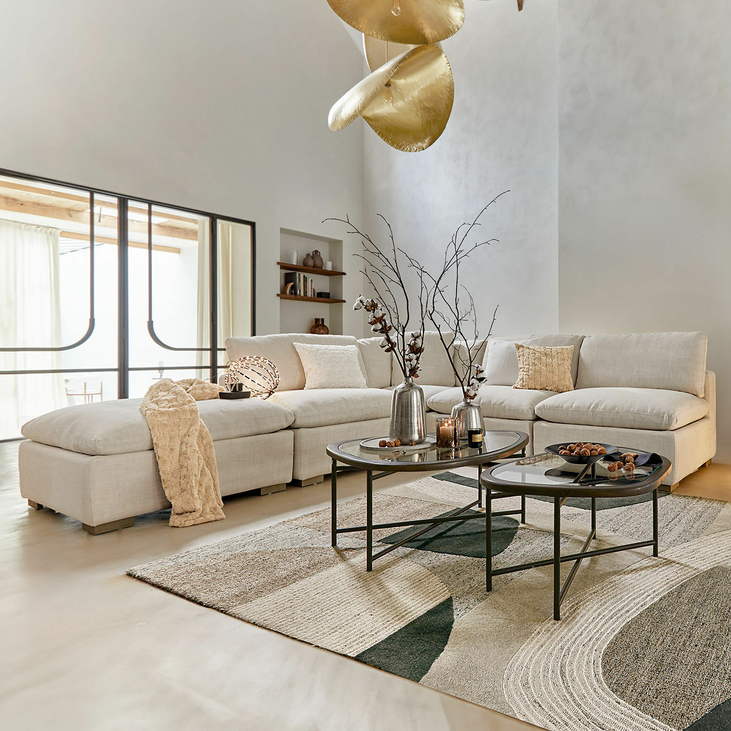 Canapé modulable Baladou Canapé d'angle beige en tissu dans un salon moderne avec tables basses en métal et décorations