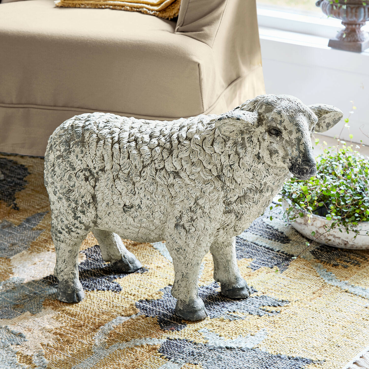 Mouton décoratif Séverac Statue de mouton en pierre grise posée sur un tapis, décoration intérieure naturelle et rustique