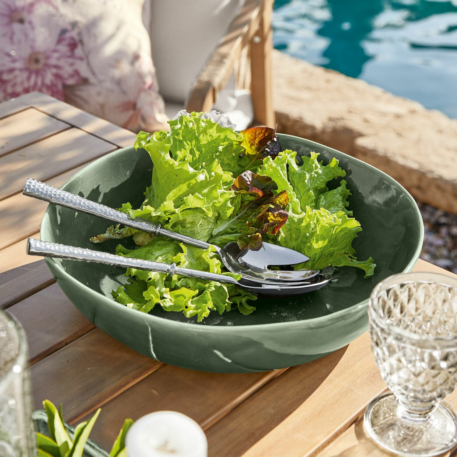 Coupe Calvi Saladier en céramique verte avec salade et couverts en argent sur table en bois en extérieur