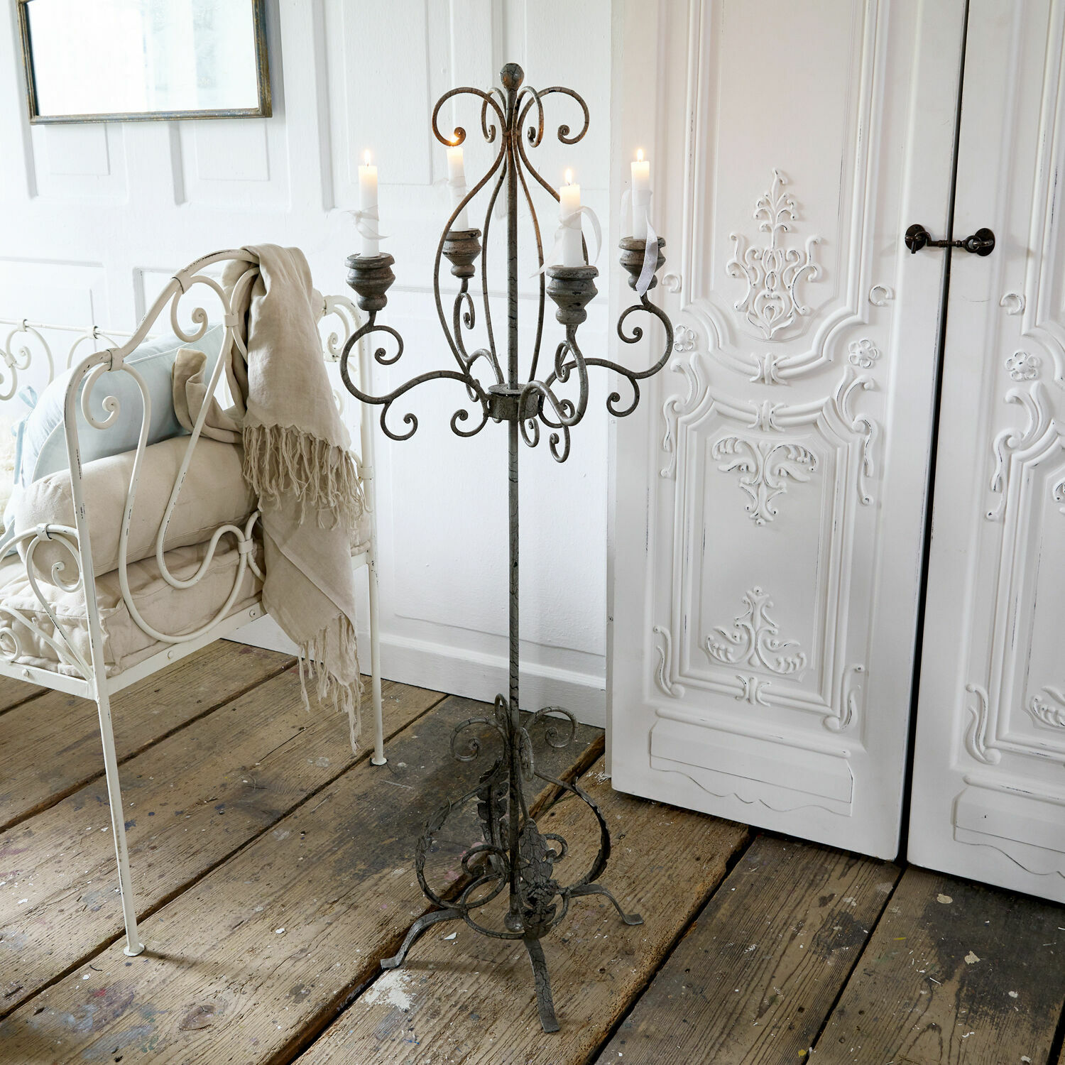 Chandelier Mandaue Chandelier en fer forgé vintage sur pied avec cinq bougies blanches sur un sol en bois rustique