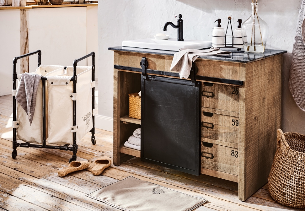 Salle de bain industrielle avec meuble en bois, tiroirs métalliques noirs et lavabo blanc sur plan en pierre