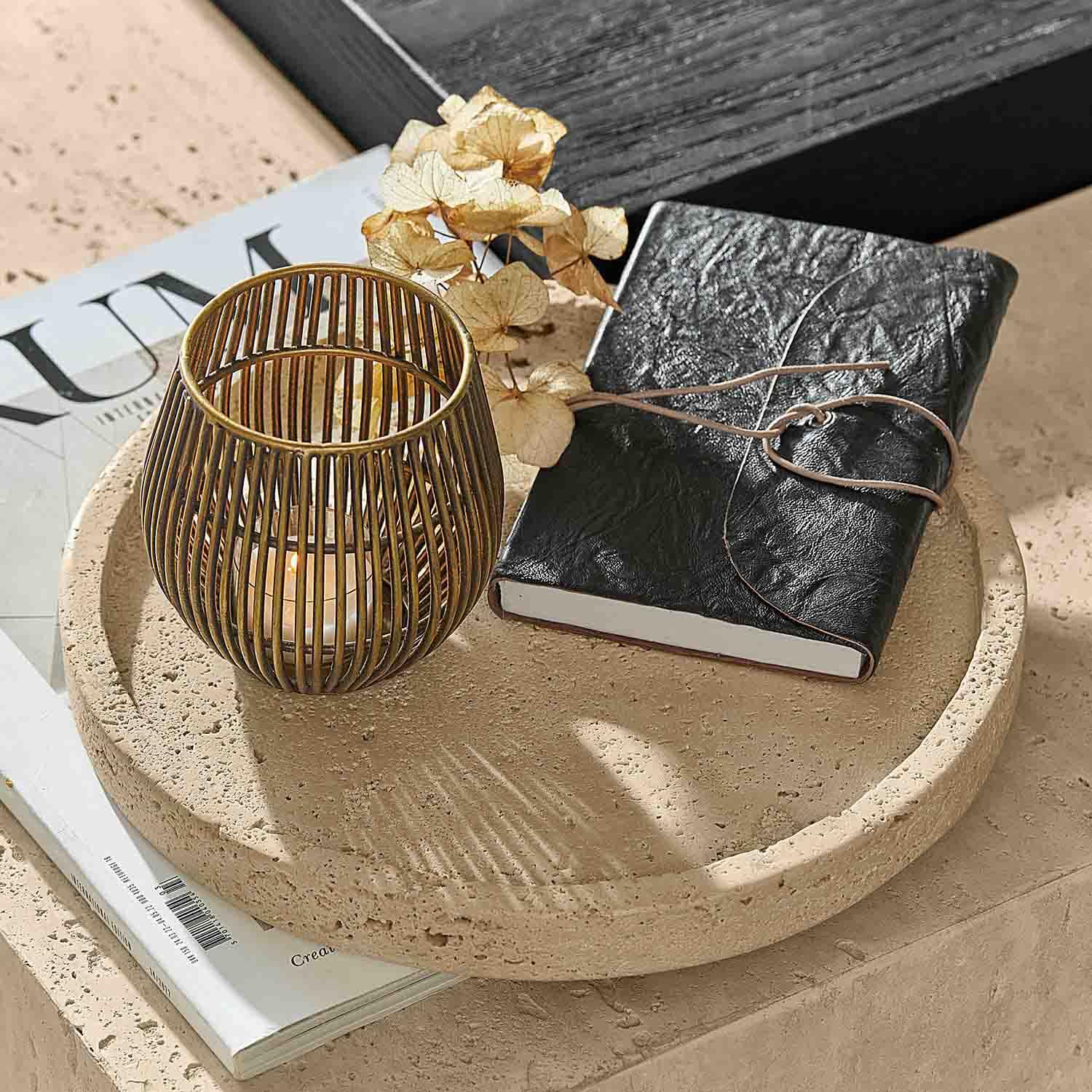 Plateau rond en pierre avec carnet en cuir noir et lanterne dorée pour bougie sur table