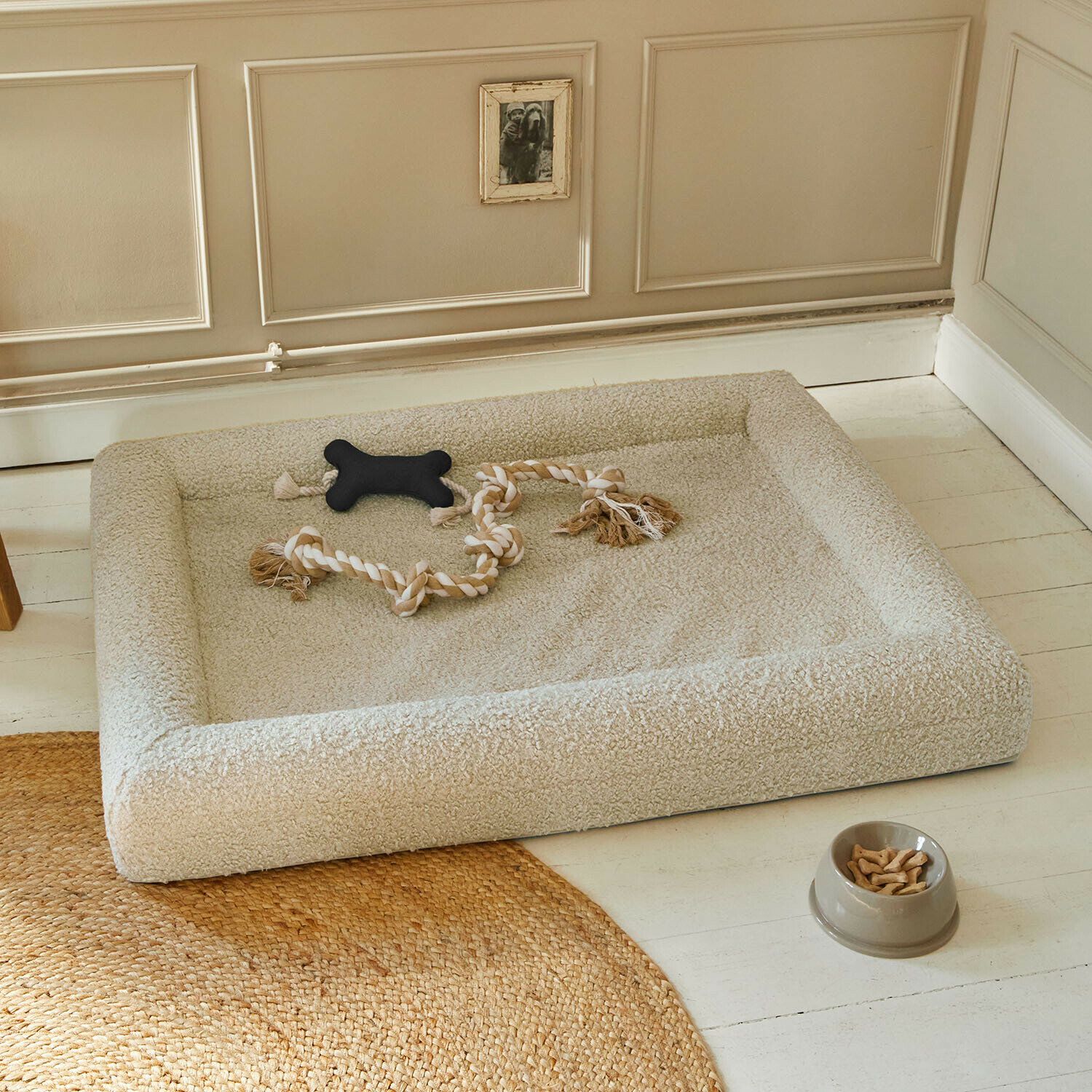 Lit pour animaux Khalima Panier beige en tissu doux pour chien avec jouets et gamelle de friandises sur le sol clair