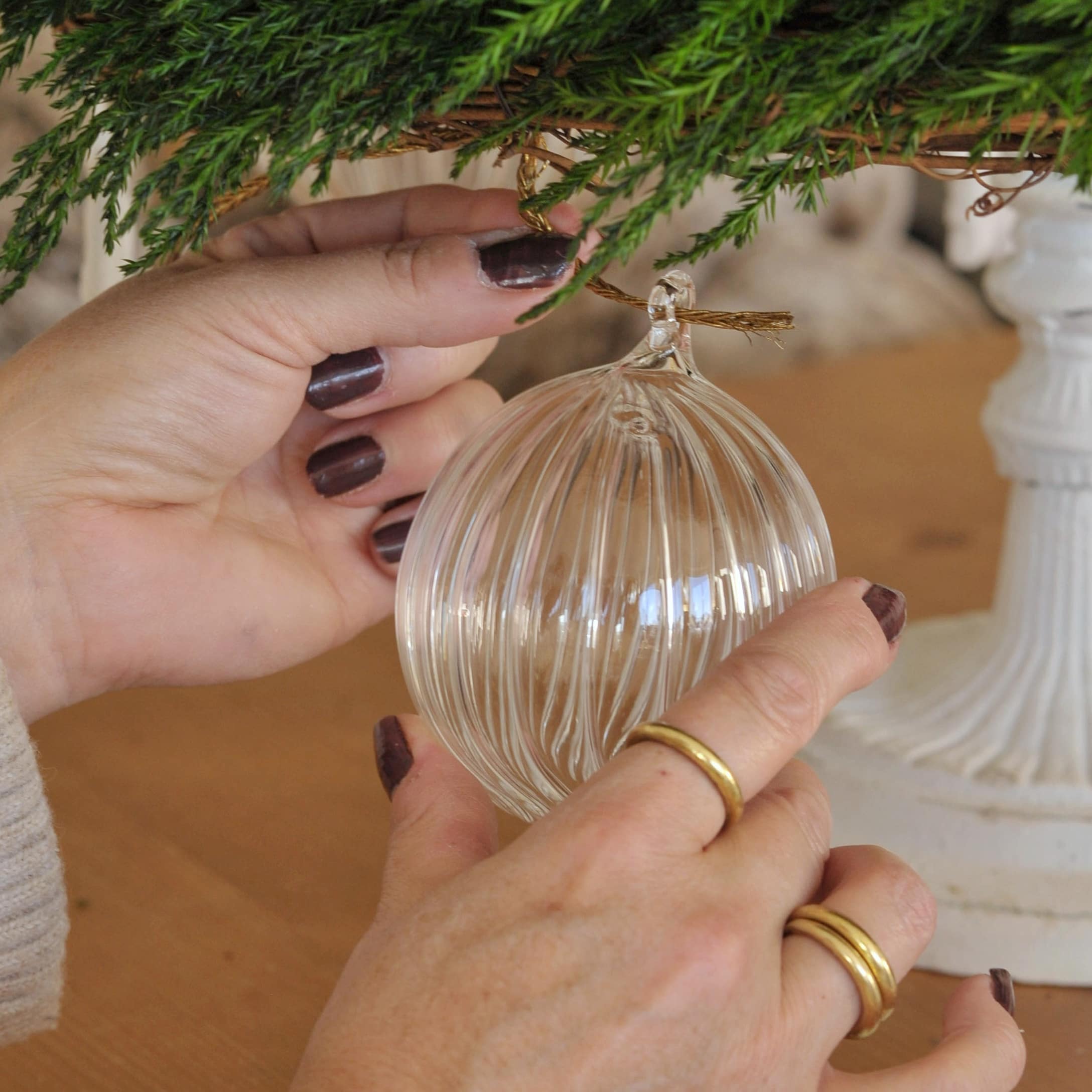 Boule de Noël en verre transparent avec rainures suspendue à une branche verte de décoration de Noël