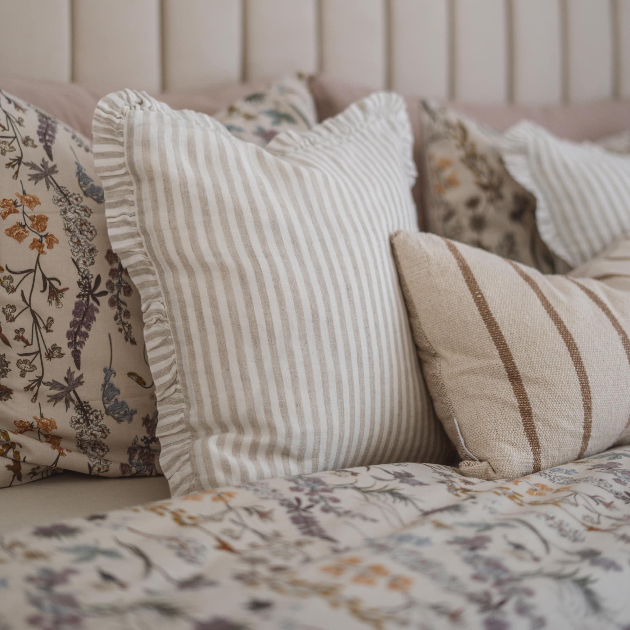 Coussins décoratifs à rayures beiges et motifs floraux sur lit, textiles pour chambre à coucher