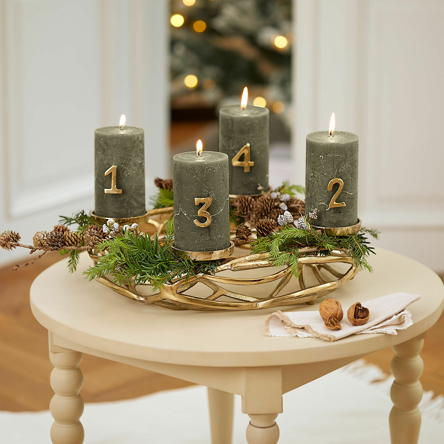 Couronne à bougies Coldfield Couronne de l'Avent verte avec quatre bougies numérotées en or sur une table beige