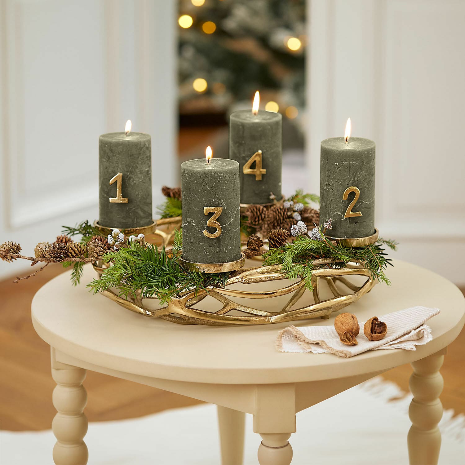 Couronne à bougies Coldfield Couronne de l'Avent verte avec quatre bougies numérotées en or sur une table beige