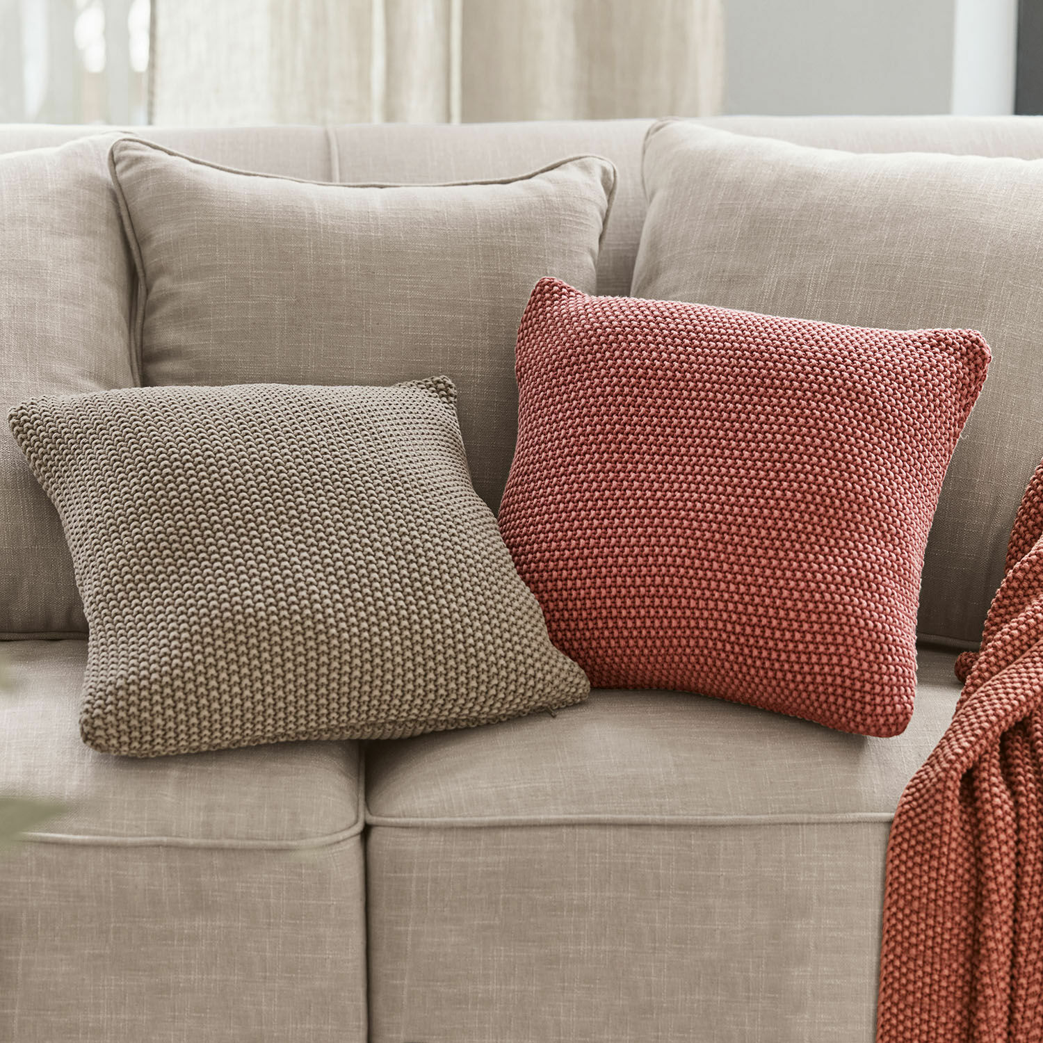 Lot de 2 housses de coussins Terry Deux coussins carrés en tricot beige et brique sur un canapé gris clair pour décoration intérieure