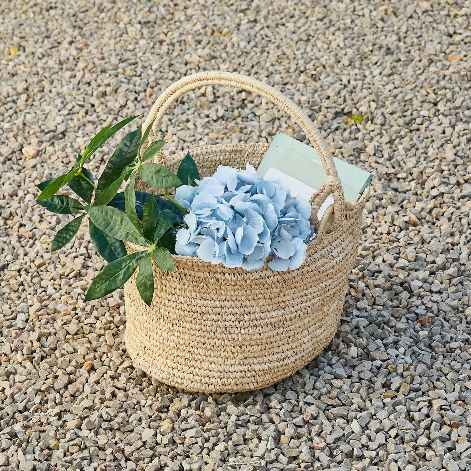 Panier Shanoura Panier tressé en herbe marine naturel avec fleurs bleues et feuilles vertes sur des cailloux